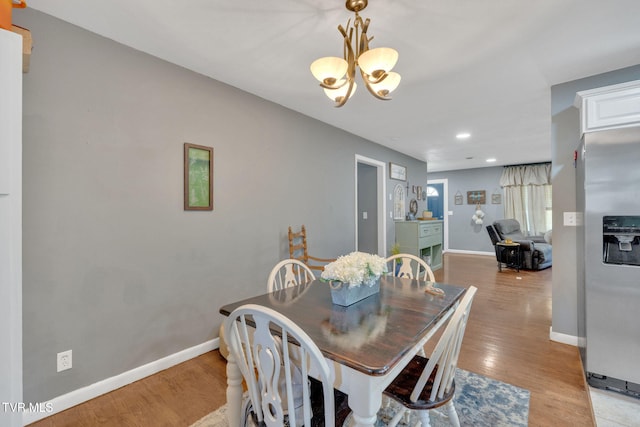 dining space featuring baseboards, recessed lighting, light wood-style flooring, and a notable chandelier