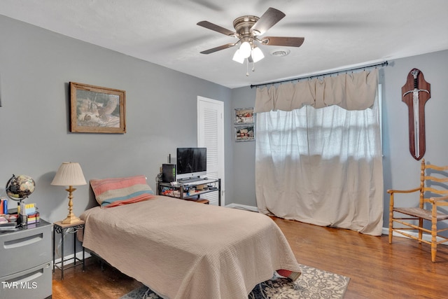 bedroom featuring a ceiling fan, baseboards, wood finished floors, and a closet