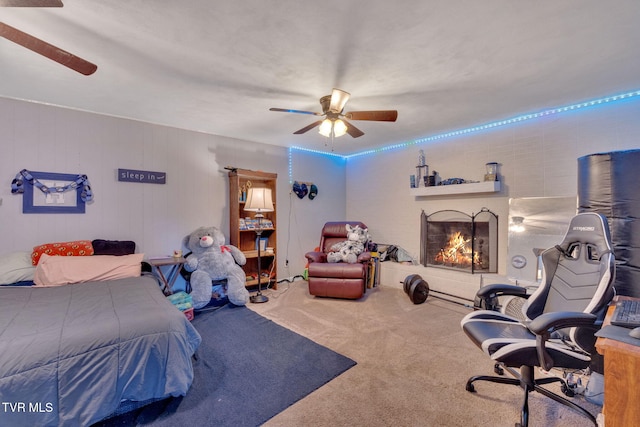 carpeted bedroom featuring a ceiling fan and a lit fireplace