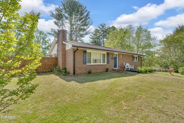view of front facade with fence, a chimney, a front lawn, and brick siding