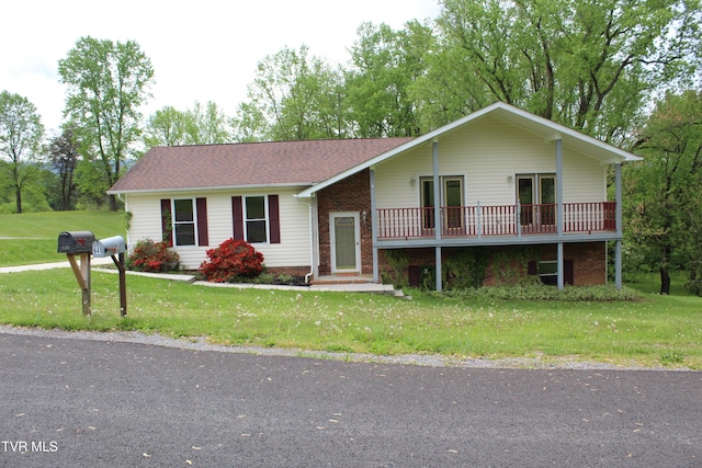 view of front of home with a front lawn, brick siding, and roof with shingles