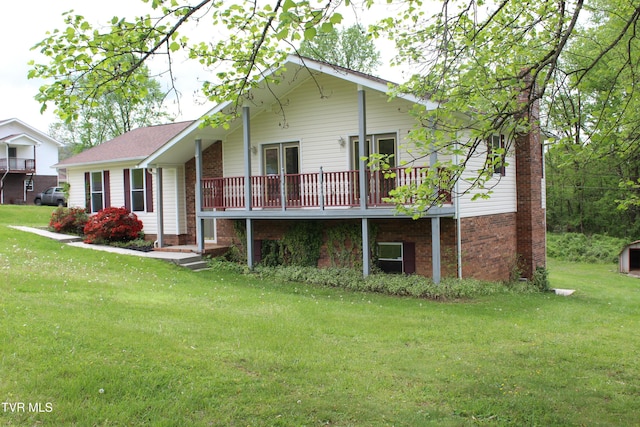 rear view of property featuring brick siding, a lawn, and roof with shingles