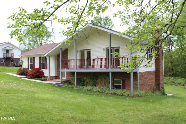 rear view of house featuring brick siding, a yard, and a deck