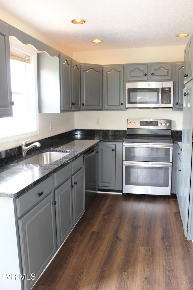 kitchen featuring a sink, gray cabinets, stainless steel appliances, dark wood-style floors, and recessed lighting