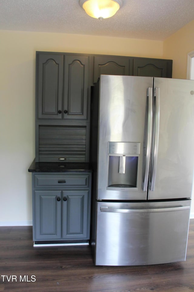 kitchen with dark wood finished floors, dark countertops, gray cabinets, and stainless steel fridge with ice dispenser