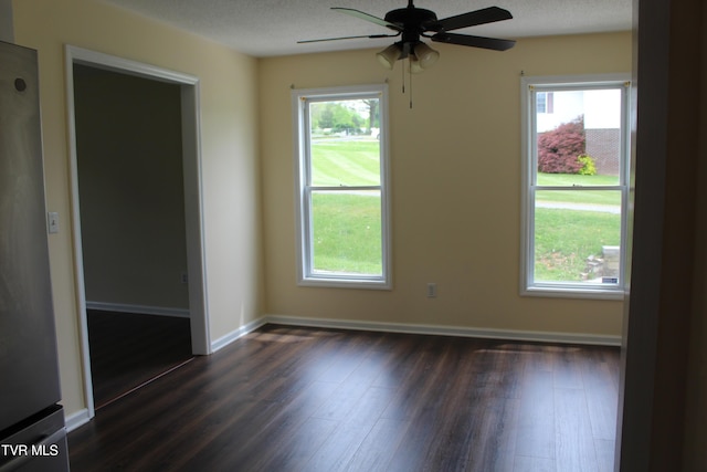 spare room with baseboards, a wealth of natural light, ceiling fan, and dark wood-style flooring