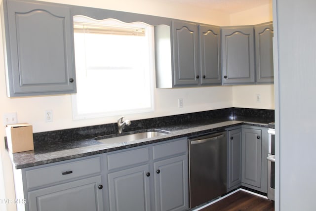 kitchen featuring dishwasher, a sink, and gray cabinets