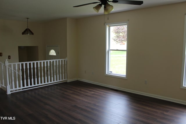 unfurnished room with ceiling fan, baseboards, visible vents, and dark wood-style floors