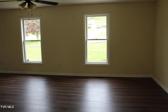 spare room with dark wood finished floors, baseboards, a ceiling fan, and visible vents