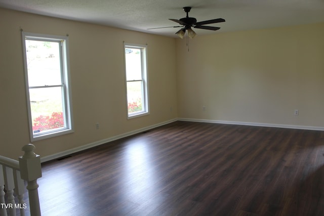 empty room with dark wood-style floors, baseboards, a ceiling fan, and visible vents