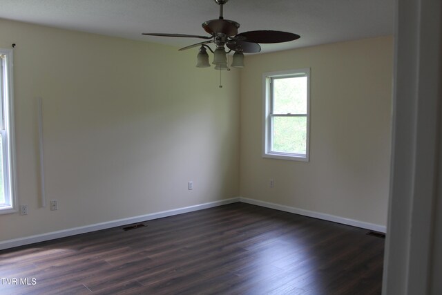 unfurnished room featuring baseboards, visible vents, ceiling fan, and dark wood-style flooring