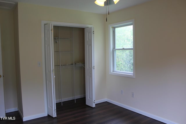 unfurnished bedroom with baseboards, dark wood-style floors, and a closet