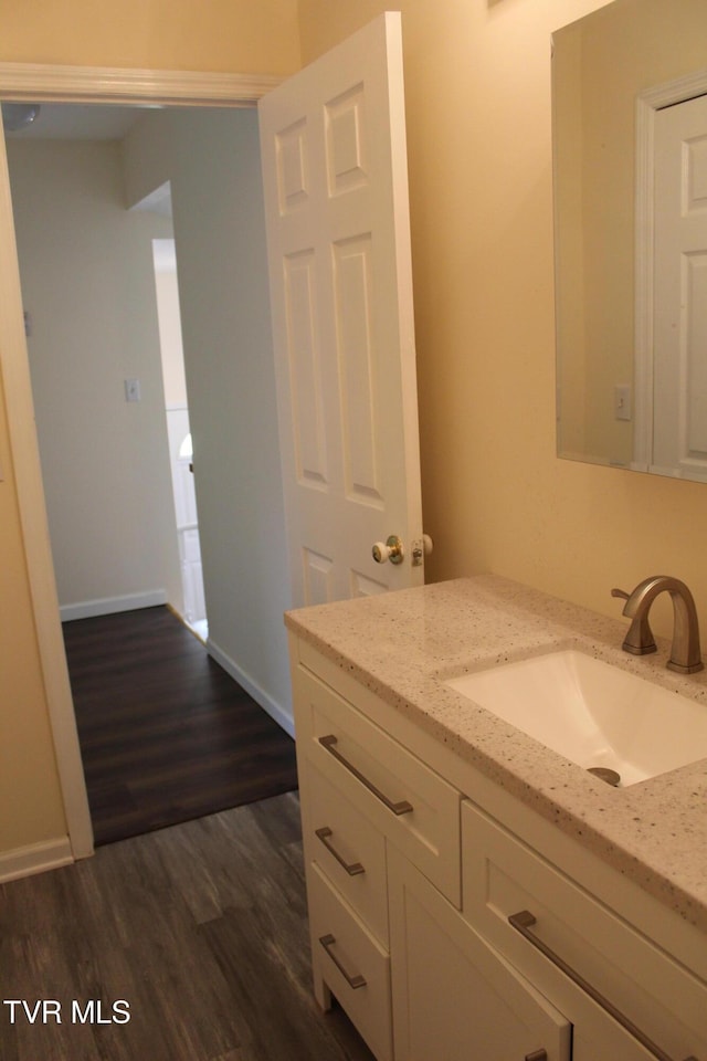 bathroom with baseboards, vanity, and wood finished floors