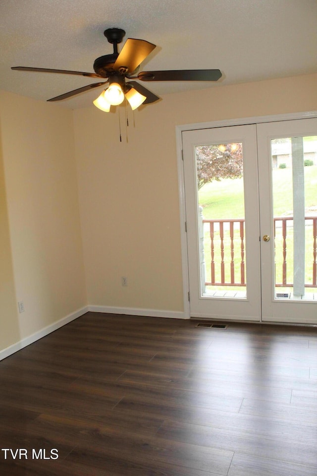 spare room featuring french doors, dark wood-style floors, ceiling fan, and a healthy amount of sunlight