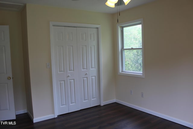 unfurnished bedroom featuring baseboards, dark wood-style flooring, and multiple windows