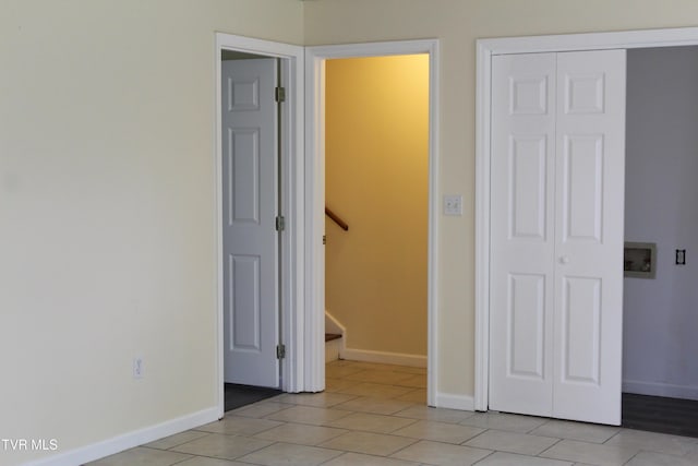 unfurnished bedroom with a closet, baseboards, and light tile patterned floors