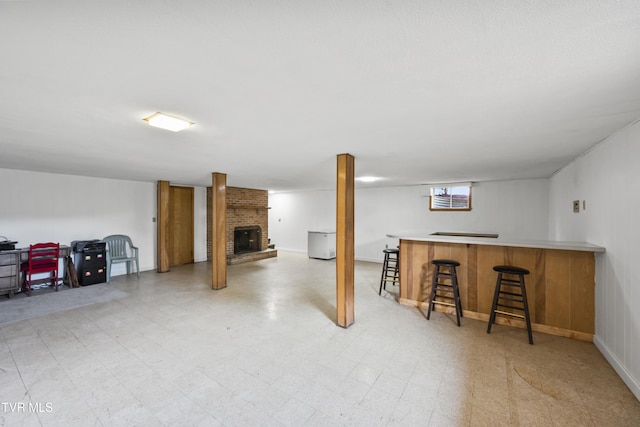 basement with a fireplace, a bar, and light floors
