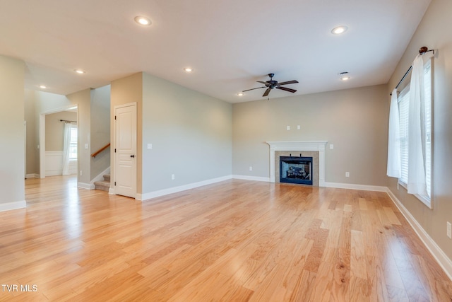 unfurnished living room featuring light wood finished floors, recessed lighting, a ceiling fan, stairway, and a tile fireplace