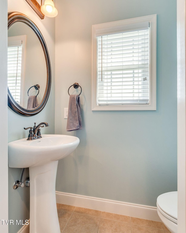 bathroom with baseboards, tile patterned flooring, and toilet