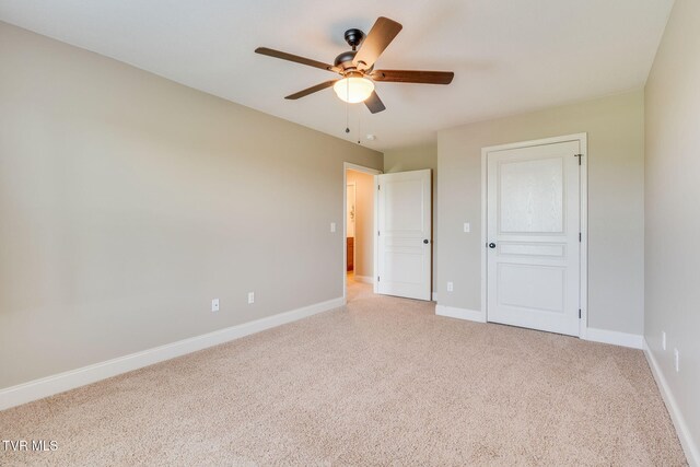 unfurnished bedroom with light carpet, a ceiling fan, and baseboards