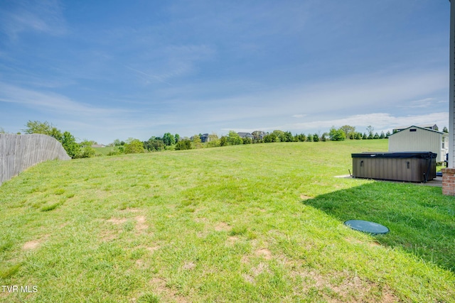 view of yard with fence, a hot tub, and a rural view