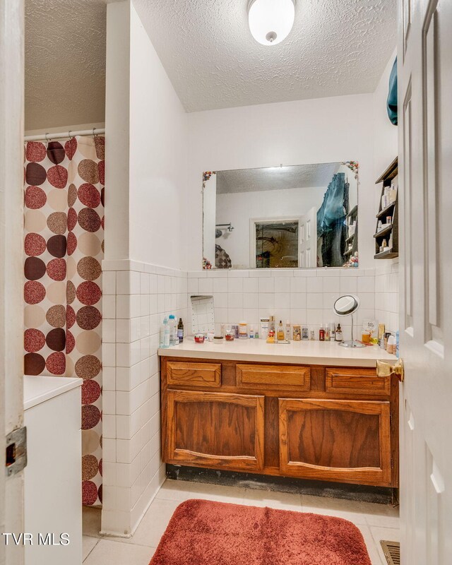 226 Delaney St, Bristol, TN 37620 - full bath with a textured ceiling, wainscoting, vanity, tile walls, and tile patterned flooring