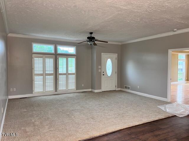 foyer entrance with ceiling fan, baseboards, ornamental molding, and visible vents