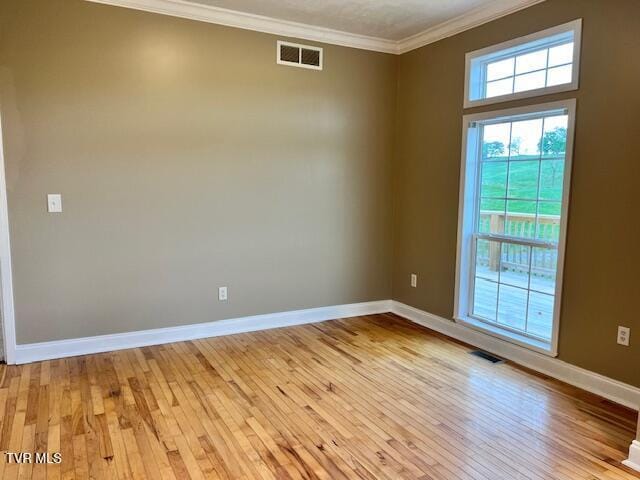 unfurnished room with baseboards, light wood-style flooring, visible vents, and crown molding