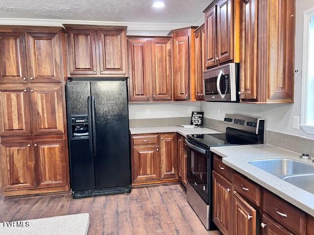 kitchen with wood finished floors, stainless steel appliances, a textured ceiling, and light countertops