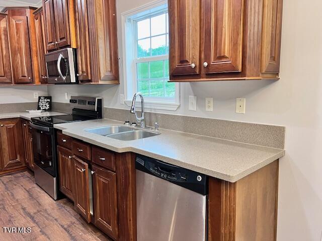 kitchen featuring appliances with stainless steel finishes, a sink, and light countertops