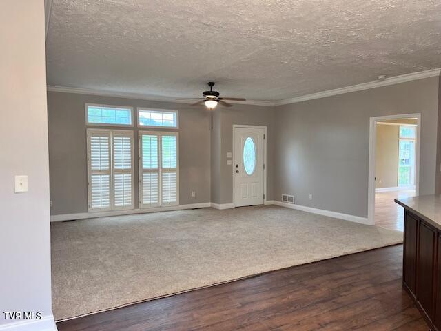 foyer entrance with a textured ceiling, ceiling fan, baseboards, ornamental molding, and visible vents