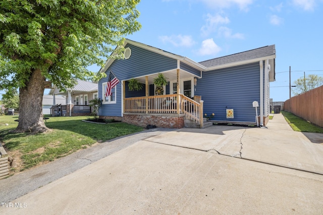bungalow-style house featuring a front lawn, fence, and covered porch
