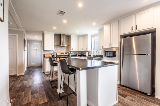 616 Towers Dr, Dandridge, TN 37725 - kitchen featuring dark countertops, wall chimney range hood, visible vents, appliances with stainless steel finishes, and white cabinetry