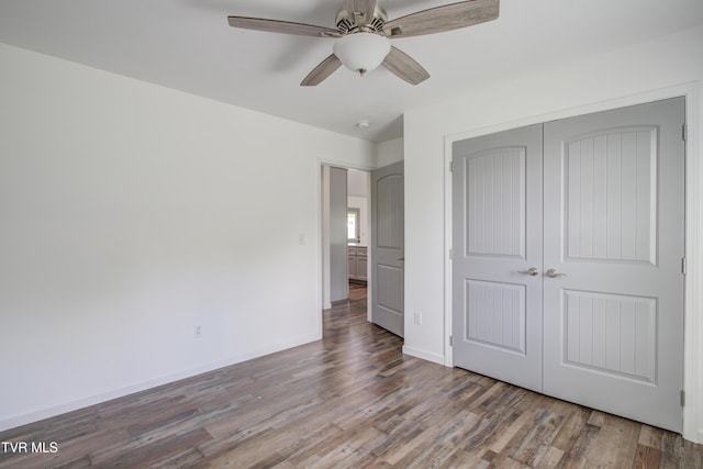 unfurnished bedroom featuring wood finished floors, a closet, baseboards, and ceiling fan
