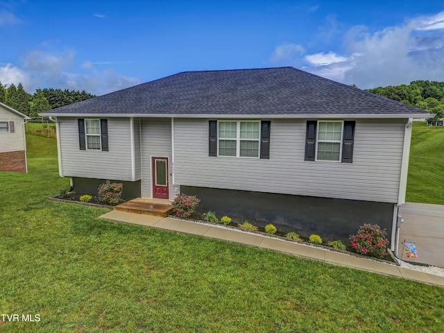raised ranch featuring a front yard and roof with shingles