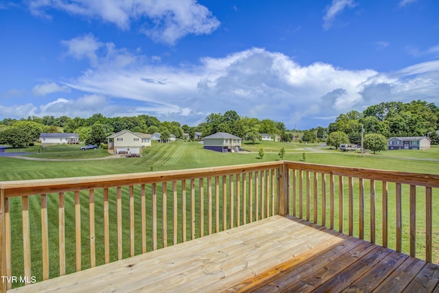 wooden terrace with view of wooded area and a yard