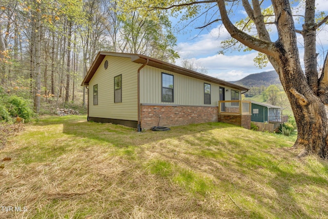 view of property exterior with a yard, a mountain view, and brick siding