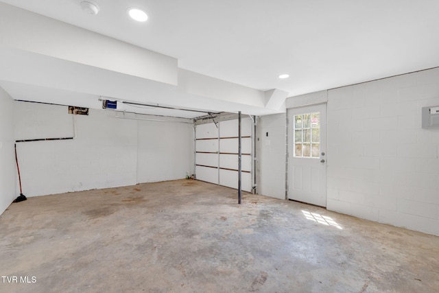 garage featuring concrete block wall and a garage door opener