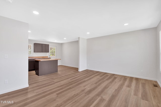 unfurnished living room with baseboards, visible vents, and light wood finished floors