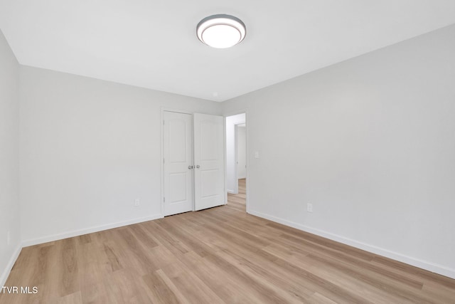 unfurnished room with baseboards and light wood-type flooring