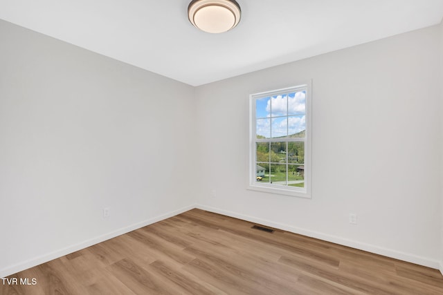 unfurnished room featuring visible vents, wood finished floors, and baseboards