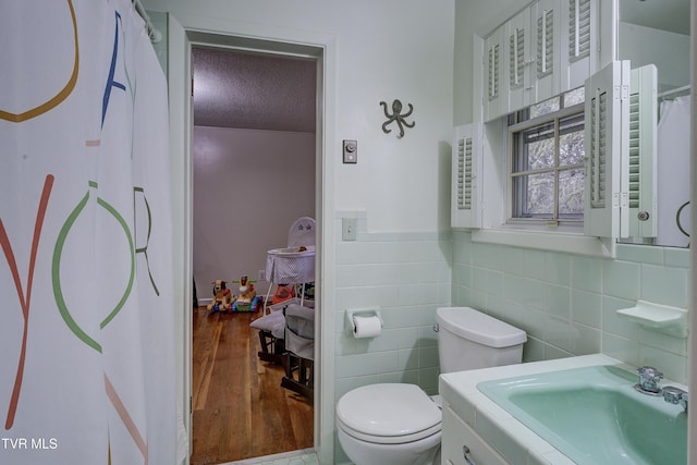 103 Dogwood Ln, Johnson City, TN 37604 - bathroom featuring a textured ceiling, toilet, tile walls, wainscoting, and wood finished floors