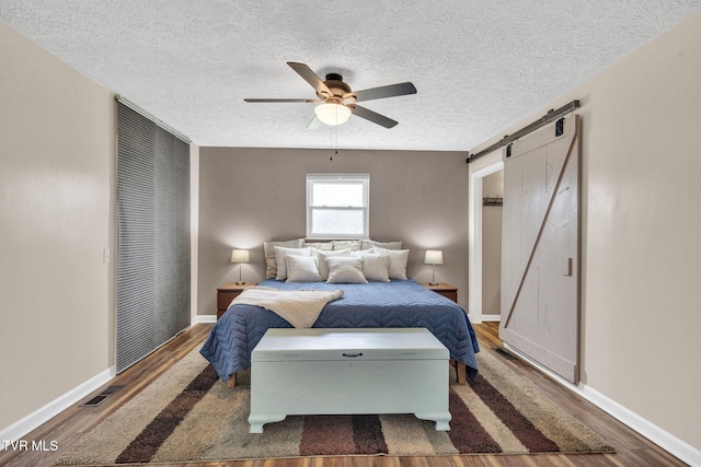 20 Chuckey College St, Chuckey, TN 37641 - bedroom with a barn door, wood finished floors, a textured ceiling, and baseboards