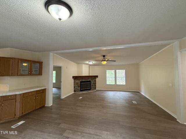 136 Gentry Mountain Rd, Erwin, TN 37650 - unfurnished living room featuring ceiling fan, a textured ceiling, a stone fireplace, visible vents, and dark wood-style floors