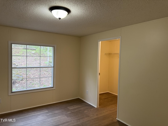 136 Gentry Mountain Rd, Erwin, TN 37650 - unfurnished bedroom with a textured ceiling, a spacious closet, dark wood-style floors, and a closet