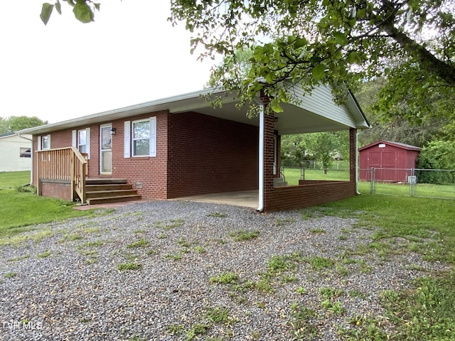 back of property with driveway, an attached carport, a lawn, fence, and brick siding
