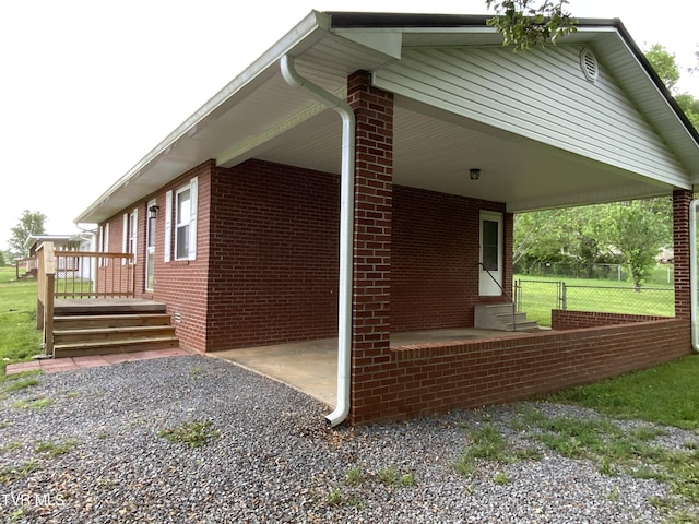 view of home's exterior featuring driveway, fence, entry steps, and brick siding