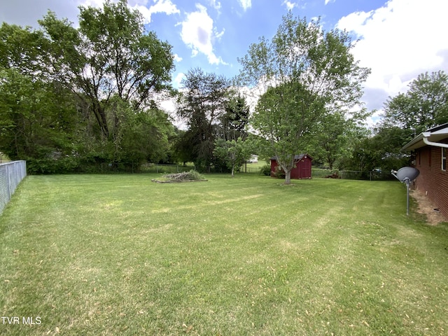 view of yard with fence, an outdoor structure, and a storage shed