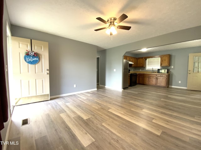 unfurnished living room with visible vents, arched walkways, ceiling fan, and light wood-style floors