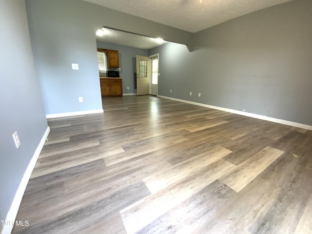 spare room featuring baseboards, a textured ceiling, and dark wood-type flooring
